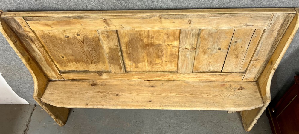An antique light pine wooden settle featuring a high three-panel backrest, flat plank seat, and solid shaped side supports. View VI
