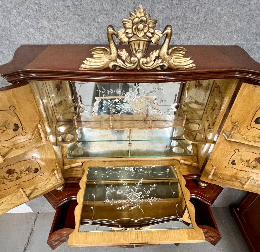 A two-tier dark walnut cocktail cabinet featuring intricate floral marquetry, a serpentine front, gilded carved accents, and turned legs with a contoured stretcher. View VII