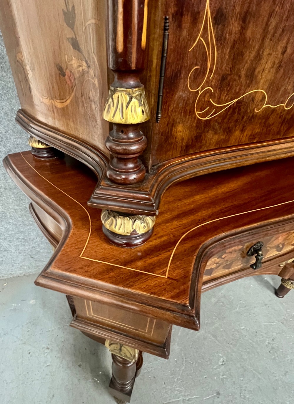 A two-tier dark walnut cocktail cabinet featuring intricate floral marquetry, a serpentine front, gilded carved accents, and turned legs with a contoured stretcher. View XI