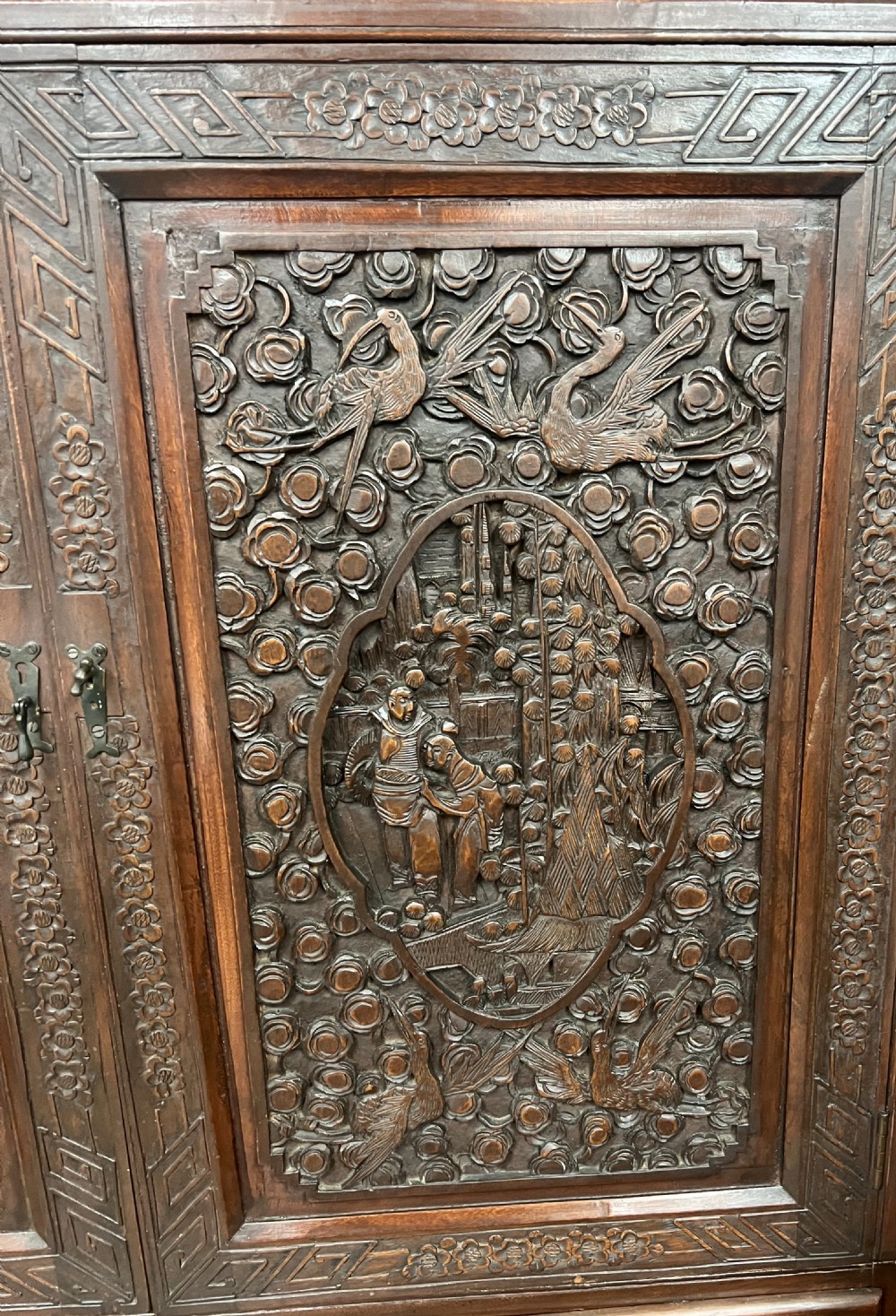 Intricately relief-carved dark camphor wood cabinet-on-chest featuring two upper cupboard doors decorated with figurative scenes above two short and one long drawer. View IV