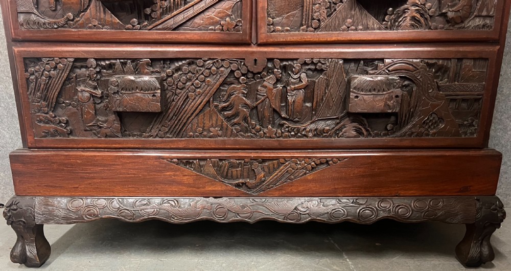 Intricately relief-carved dark camphor wood cabinet-on-chest featuring two upper cupboard doors decorated with figurative scenes above two short and one long drawer. View VII