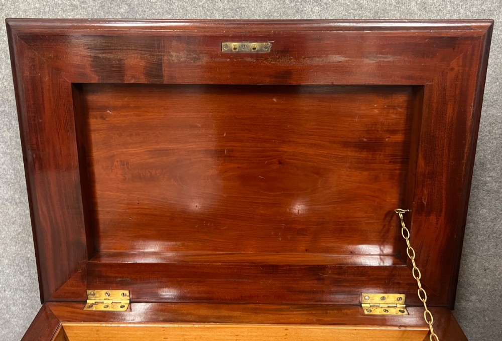 A sarcophagus-shaped antique mahogany wine cellarette with a flared lid, tapered sides, and carved turned feet. View VI
