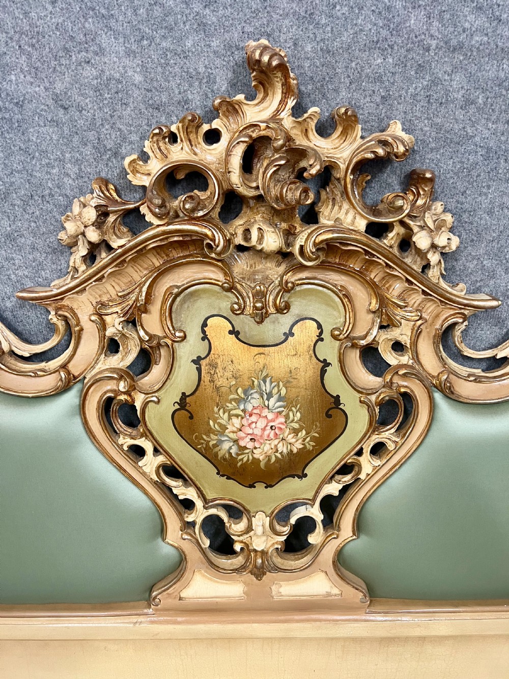An ornate French Rococo style king size bed frame featuring cream painted and carved wood with gilded accents, sage green upholstered headboard panels, and hand-painted floral cartouches. View VI