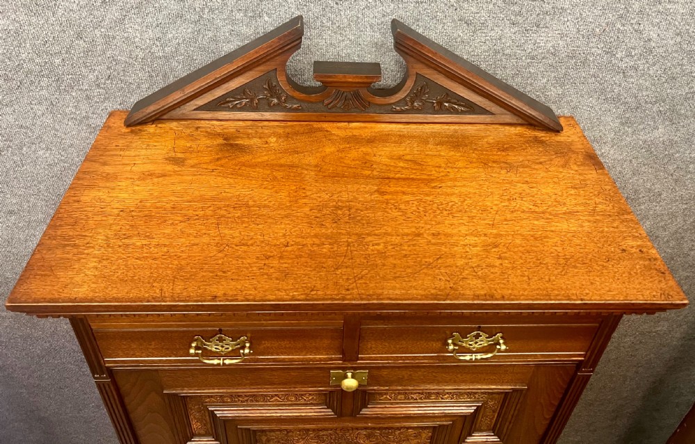 A tall dark timber escritoire desk featuring a fall-front writing surface with geometric panelling, brass drop handles, and multiple storage drawers below. View V