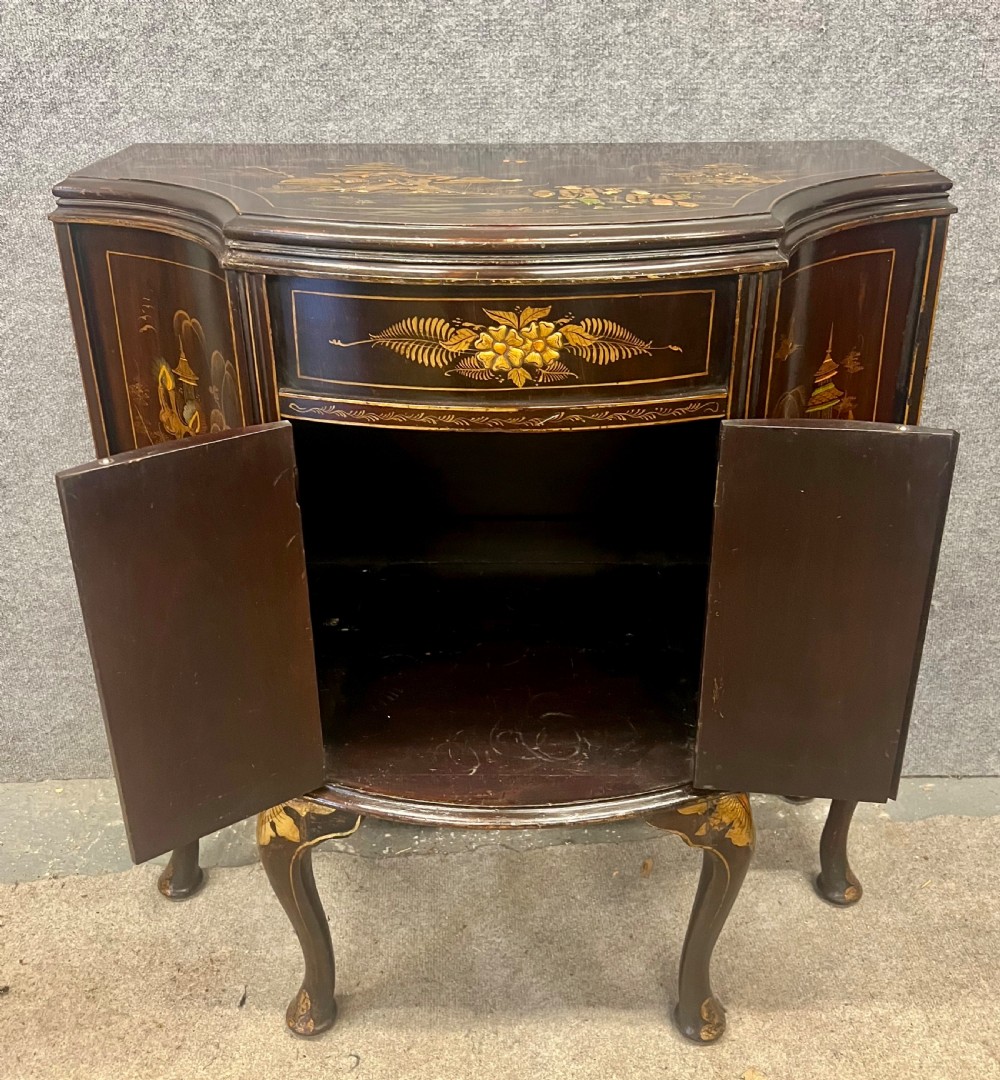A dark lacquered bow-front Chinoiserie cabinet featuring gilded pictorial landscapes and cabriole legs. View II