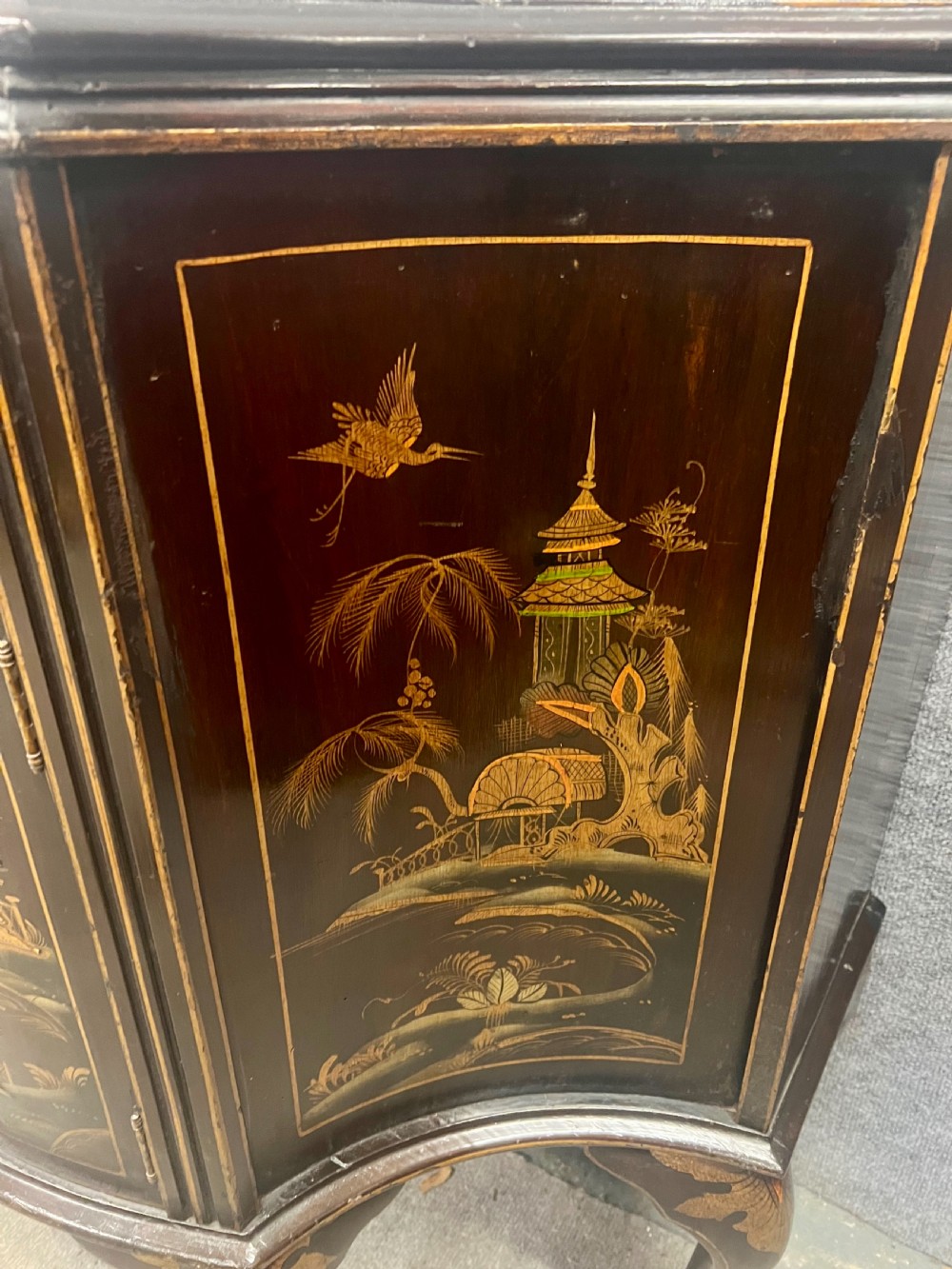 A dark lacquered bow-front Chinoiserie cabinet featuring gilded pictorial landscapes and cabriole legs. View VI