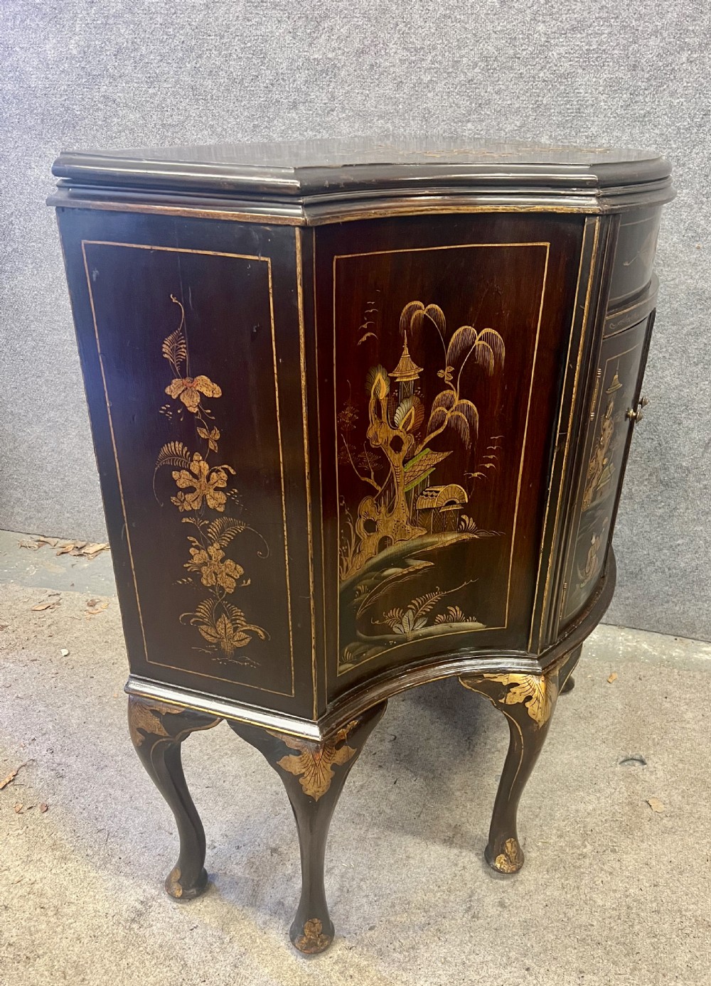 A dark lacquered bow-front Chinoiserie cabinet featuring gilded pictorial landscapes and cabriole legs. View VII