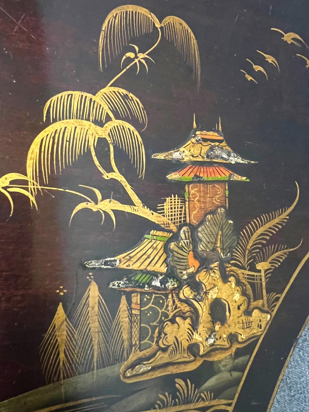 A dark lacquered bow-front Chinoiserie cabinet featuring gilded pictorial landscapes and cabriole legs. View X
