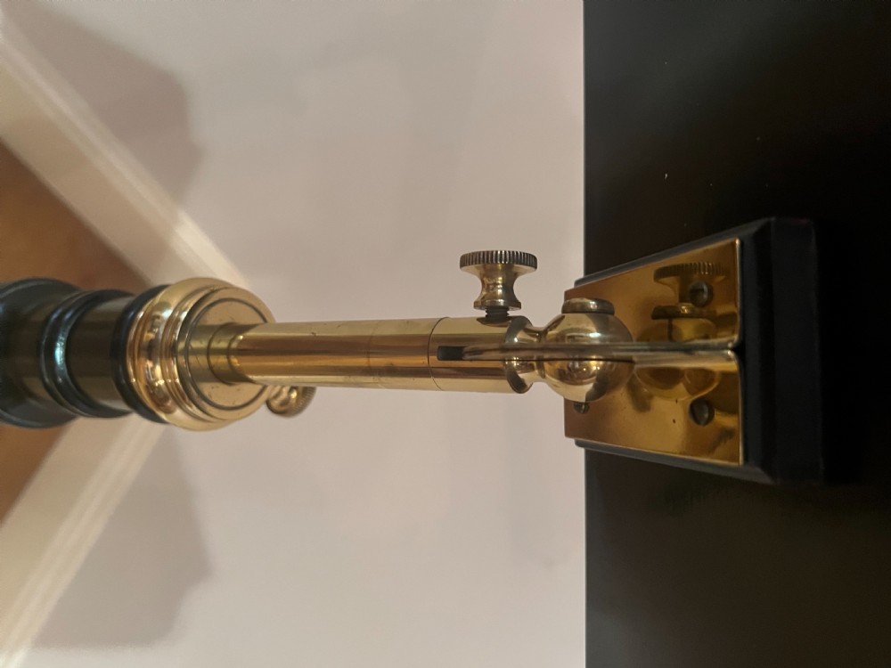 An ebonised wooden reading stand featuring a flat adjustable rest with brass page retainers, mounted on a turned column with a brass height adjustment fitting and a tripod base. View VI