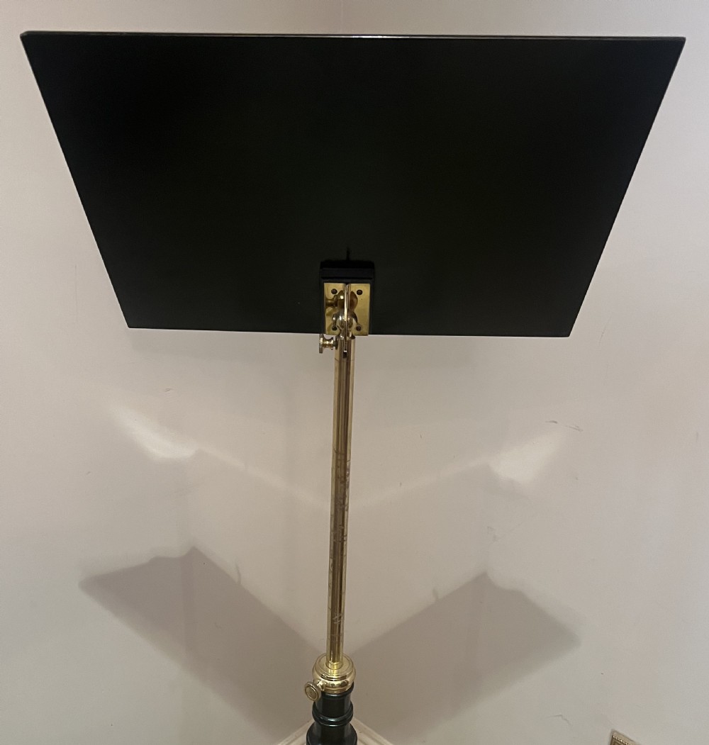 An ebonised wooden reading stand featuring a flat adjustable rest with brass page retainers, mounted on a turned column with a brass height adjustment fitting and a tripod base. View VIII