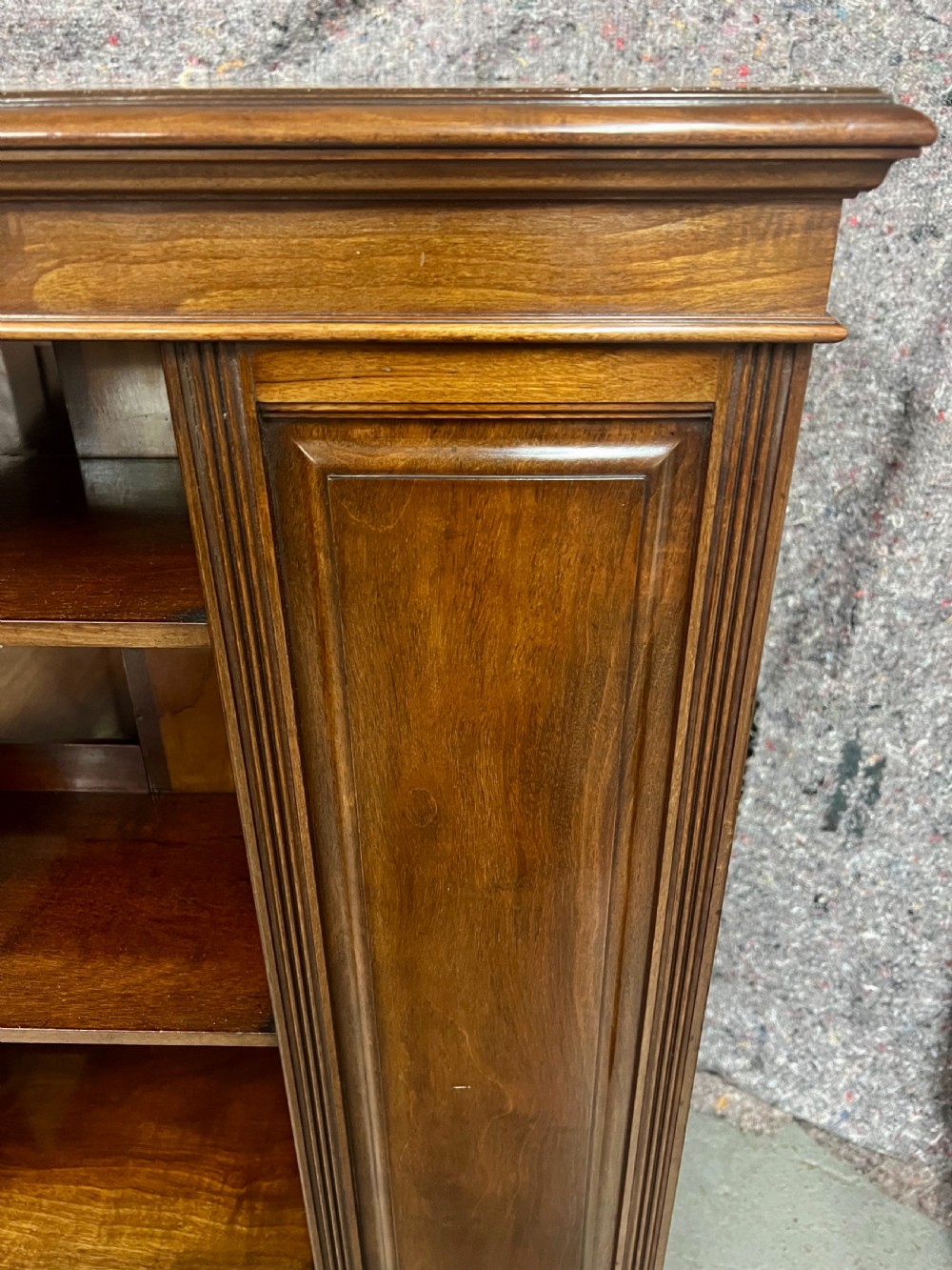 A four-sided warm brown wooden revolving bookcase featuring multiple tiers of open shelving, corner panel details, and a moulded top cornice. View IV