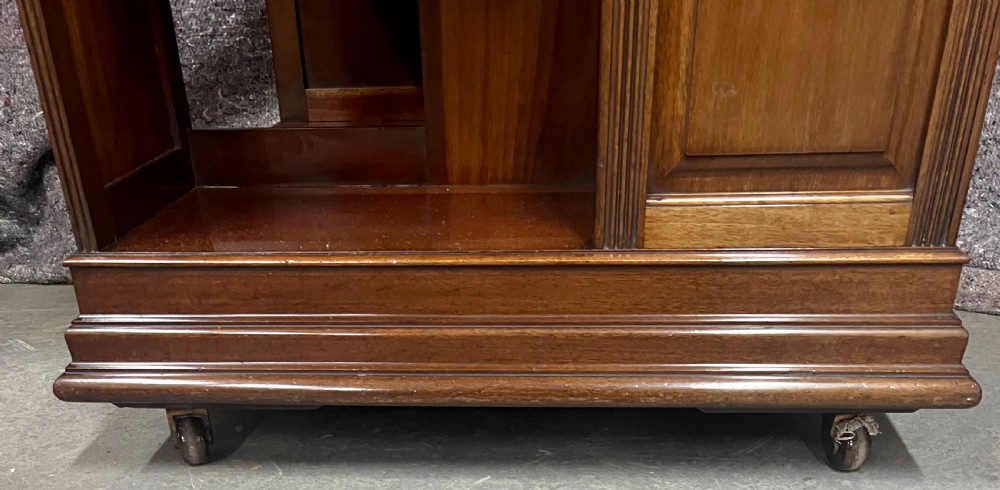 A four-sided warm brown wooden revolving bookcase featuring multiple tiers of open shelving, corner panel details, and a moulded top cornice. View IX