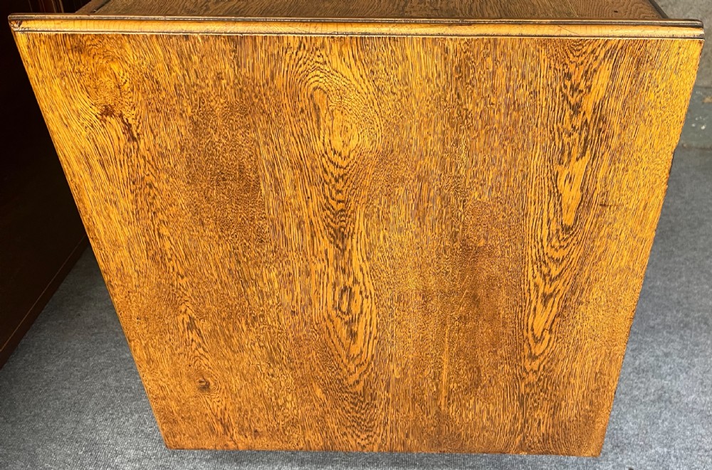 A tall Edwardian golden oak safe cabinet featuring a mirrored upper door panel, pronounced wood grain, and four drawers with metal bail handles. View VII