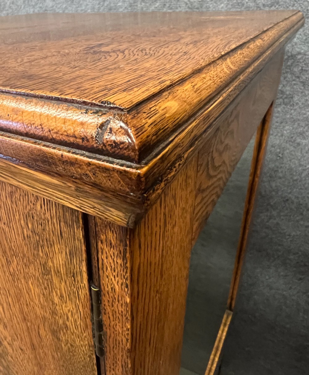 A tall Edwardian golden oak safe cabinet featuring a mirrored upper door panel, pronounced wood grain, and four drawers with metal bail handles. View X