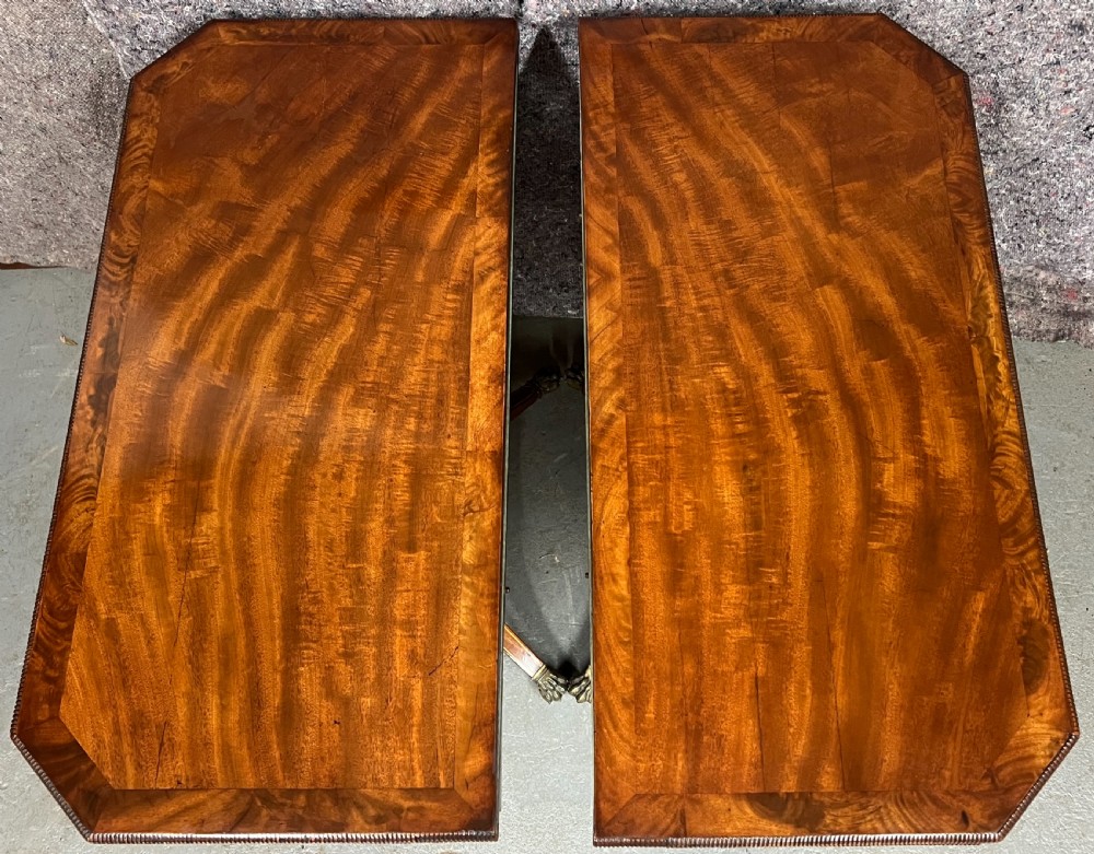 A pair of Regency flame mahogany fold-over card tables featuring boxwood inlay, reeded edges, and pedestal bases with splayed legs ending in brass paw castors. View VII