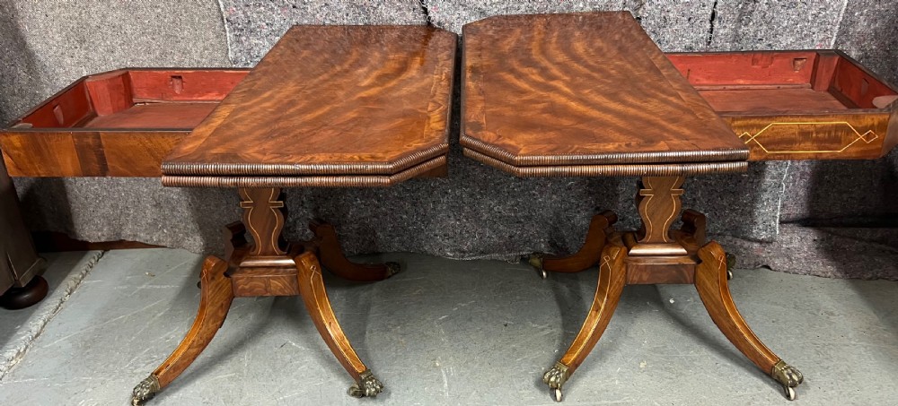 A pair of Regency flame mahogany fold-over card tables featuring boxwood inlay, reeded edges, and pedestal bases with splayed legs ending in brass paw castors. View X
