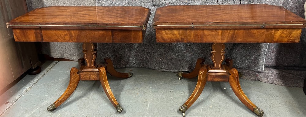 A pair of Regency flame mahogany fold-over card tables featuring boxwood inlay, reeded edges, and pedestal bases with splayed legs ending in brass paw castors. View XI