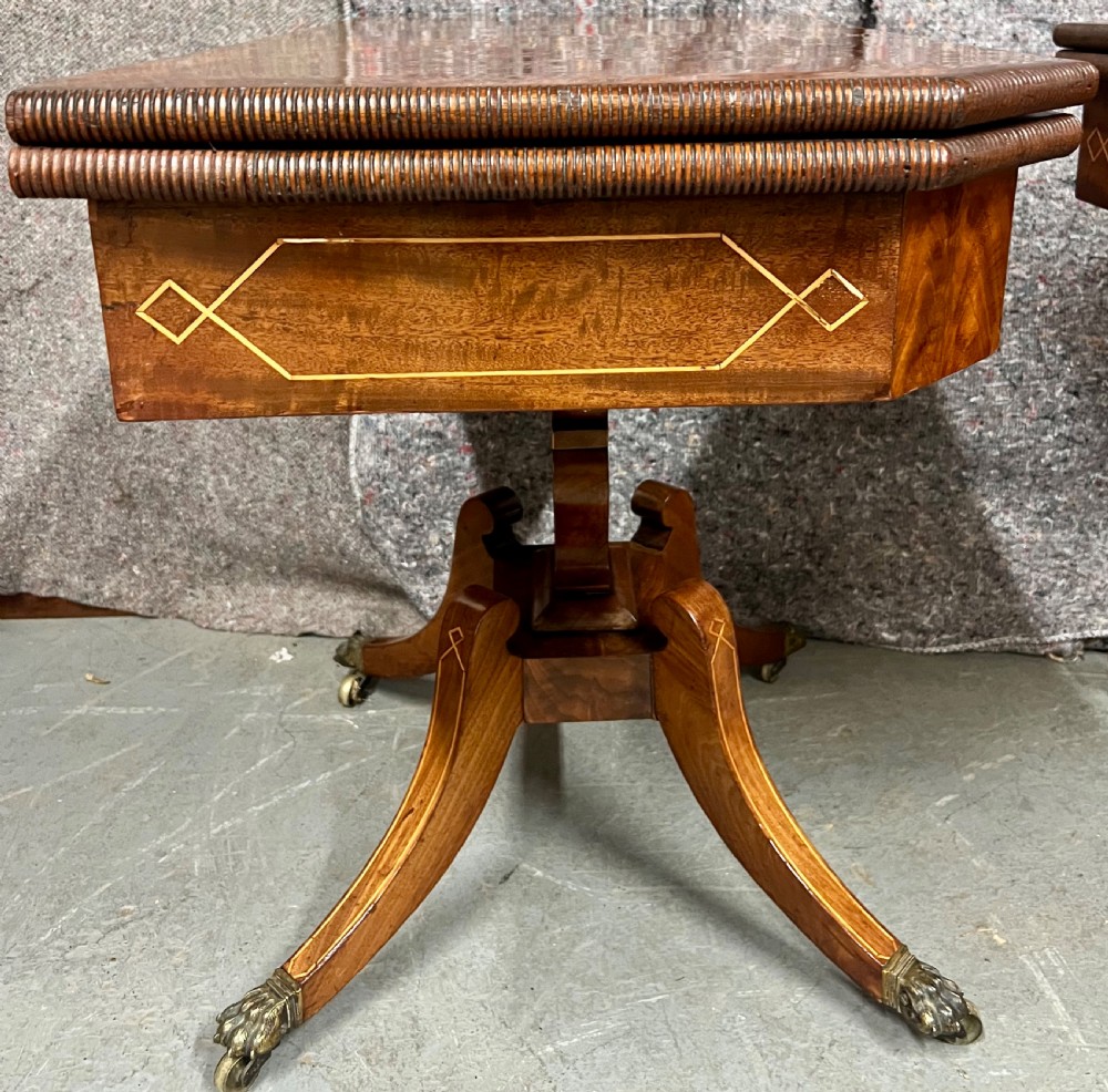 A pair of Regency flame mahogany fold-over card tables featuring boxwood inlay, reeded edges, and pedestal bases with splayed legs ending in brass paw castors. View XIV
