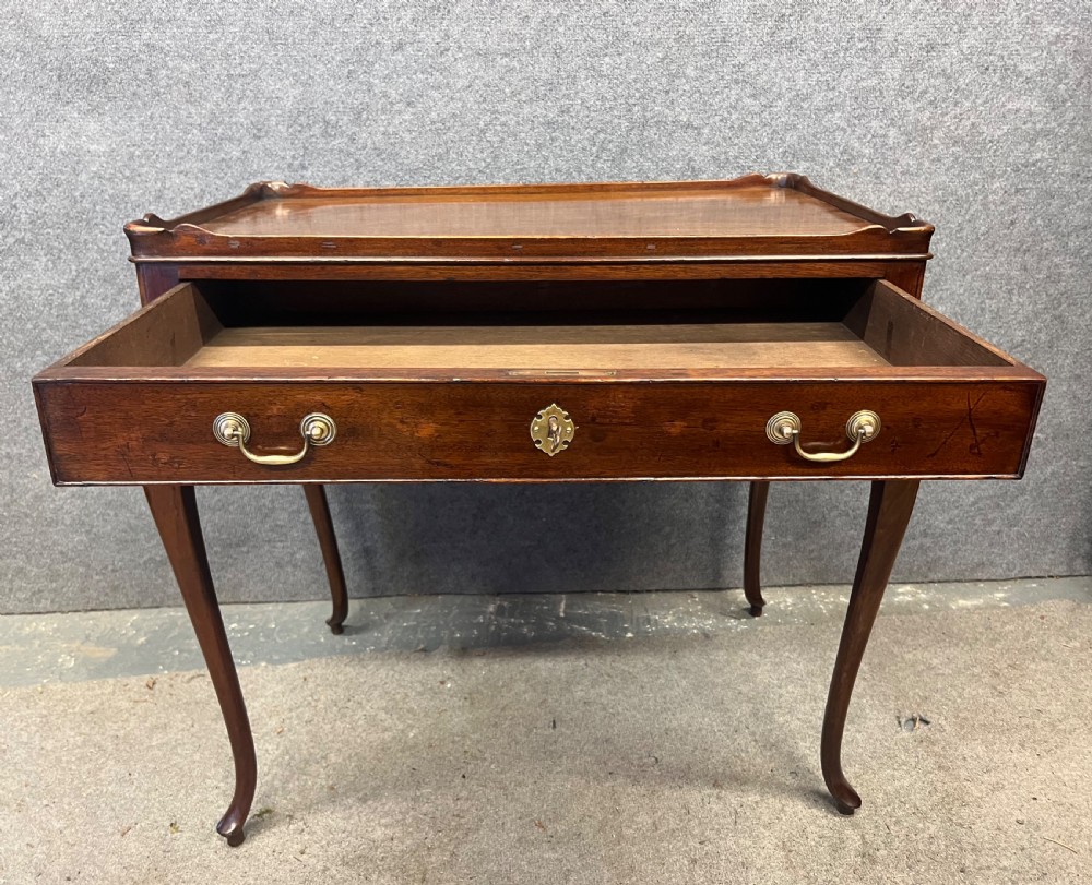 A Georgian mahogany silver table featuring a raised gallery top, a single drawer with brass handles, and slender cabriole legs. View V