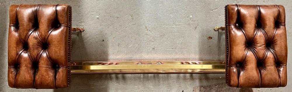 An antique brass and copper club fender featuring two button-tufted brown leather corner seats with brass stud detailing set on a low metal base. View III