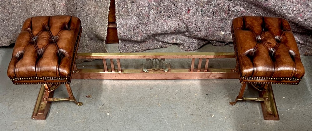 An antique brass and copper club fender featuring two button-tufted brown leather corner seats with brass stud detailing set on a low metal base. View VIII