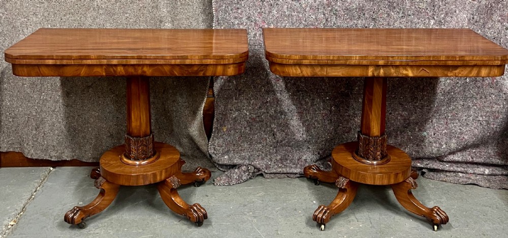 A pair of antique flame mahogany fold-over console tables featuring central carved pedestal columns and claw feet with castors. View II