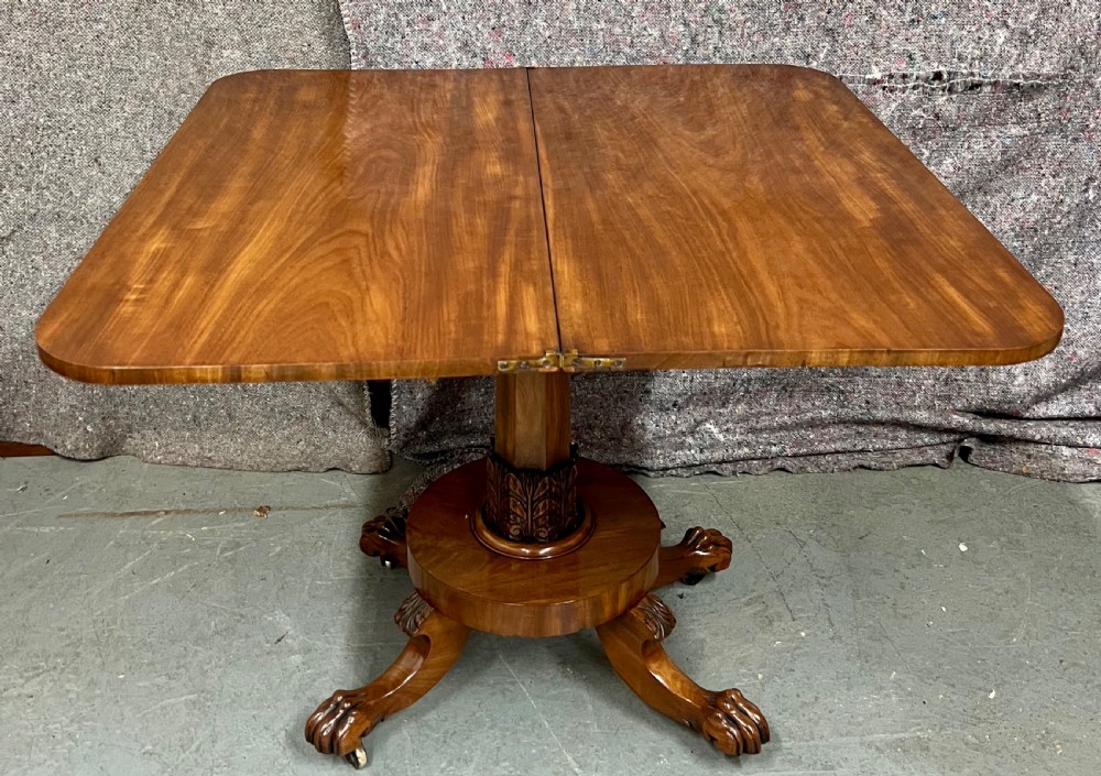 A pair of antique flame mahogany fold-over console tables featuring central carved pedestal columns and claw feet with castors. View IV