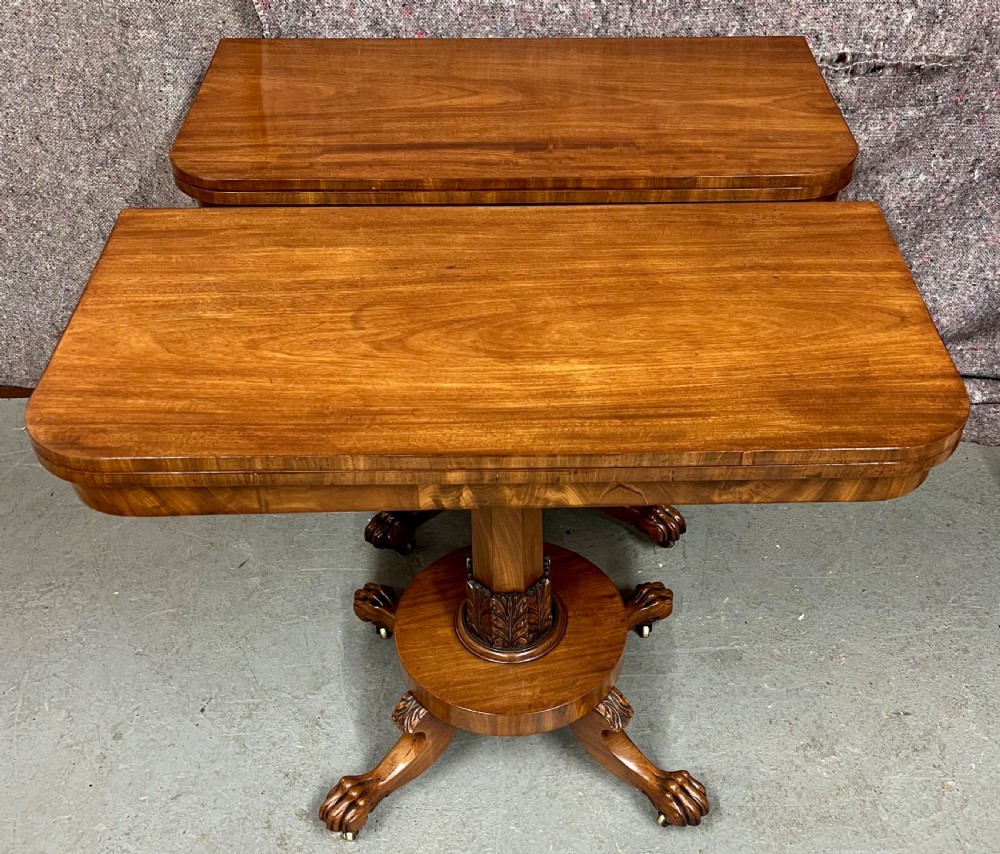 A pair of antique flame mahogany fold-over console tables featuring central carved pedestal columns and claw feet with castors. View IX