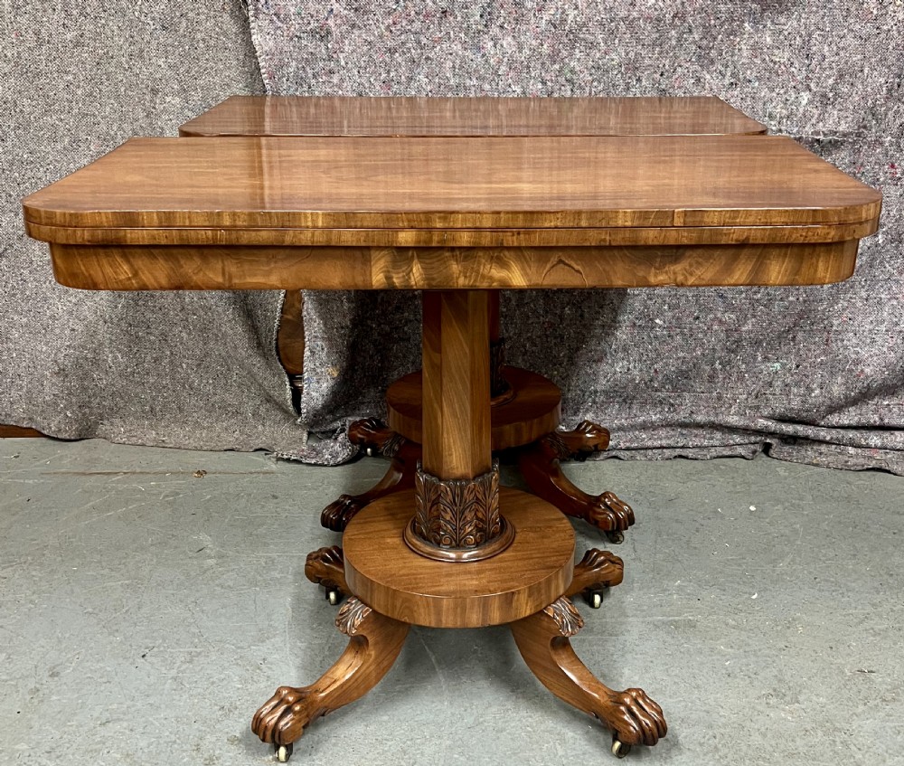 A pair of antique flame mahogany fold-over console tables featuring central carved pedestal columns and claw feet with castors. View X