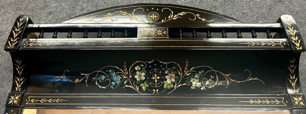 An Aesthetic Movement ebonised wooden overmantel mirror featuring hand-painted floral panels, gold foliage accents, and a curved top cresting. View VI