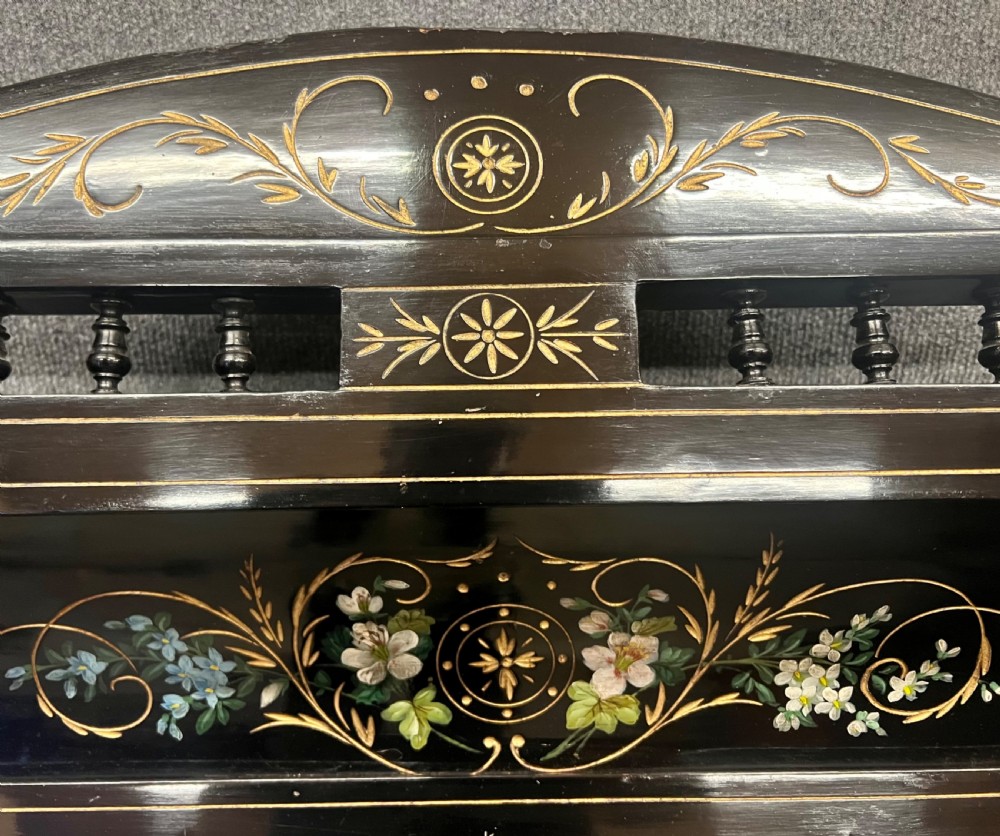 An Aesthetic Movement ebonised wooden overmantel mirror featuring hand-painted floral panels, gold foliage accents, and a curved top cresting. View X