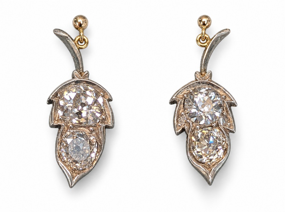 Pair of antique Victorian drop earrings featuring foliage motif mounts set with old cut diamonds suspended from gold hook fittings.
