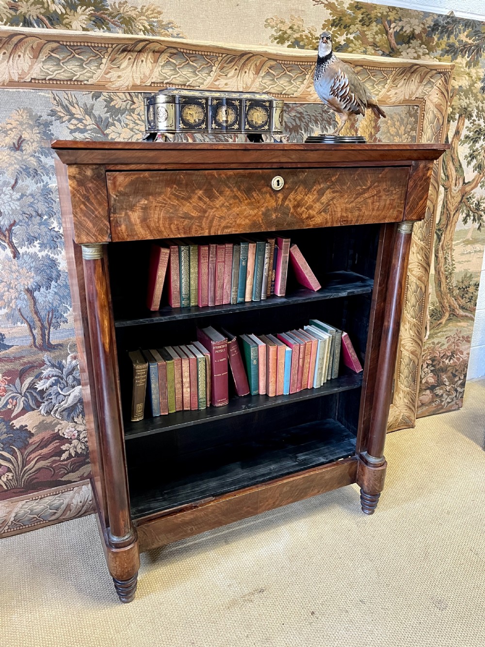 An antique French Empire open bookcase crafted from flame mahogany, featuring three open shelves, a top frieze drawer, and side column supports. View II