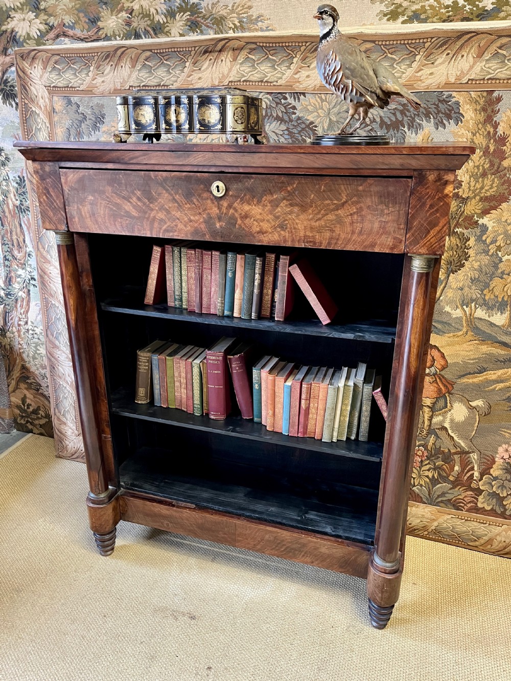 An antique French Empire open bookcase crafted from flame mahogany, featuring three open shelves, a top frieze drawer, and side column supports. View III