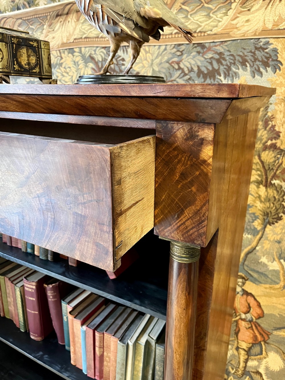 An antique French Empire open bookcase crafted from flame mahogany, featuring three open shelves, a top frieze drawer, and side column supports. View VI
