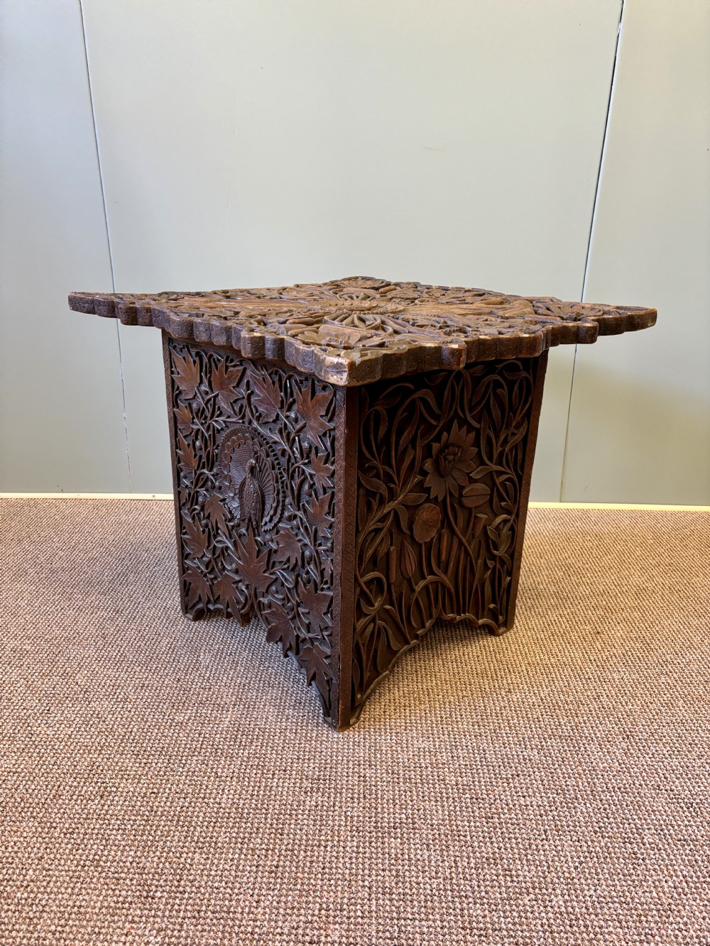 A square dark hardwood side table featuring intricate relief carvings of lotus flowers and foliage across the top and side panels. View IV