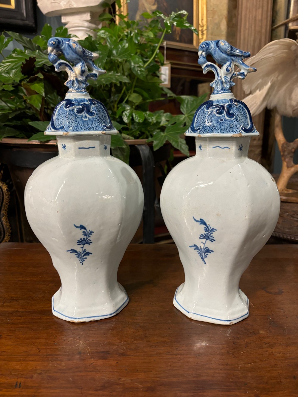 A pair of octagonal 18th-century Dutch Delftware lidded vases featuring blue hand-painted scenes within scrollwork cartouches and topped with bird finials. View IV