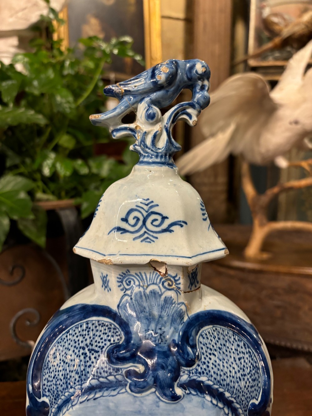 A pair of octagonal 18th-century Dutch Delftware lidded vases featuring blue hand-painted scenes within scrollwork cartouches and topped with bird finials. View VI