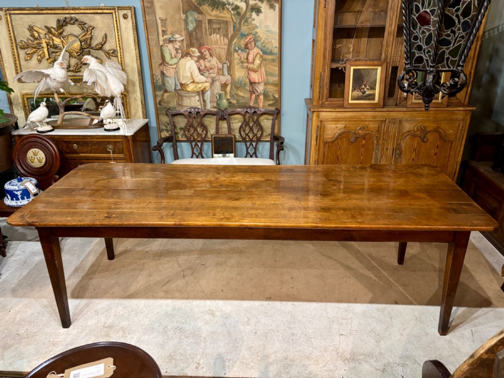 A long 19th-century French farmhouse dining table in warm brown wood with a polished plank top and square tapered legs. View II