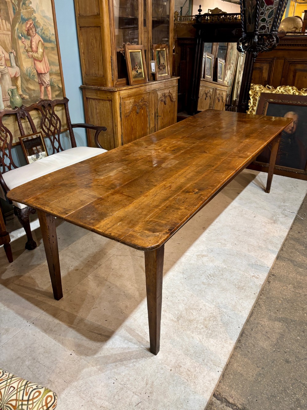 A long 19th-century French farmhouse dining table in warm brown wood with a polished plank top and square tapered legs. View III