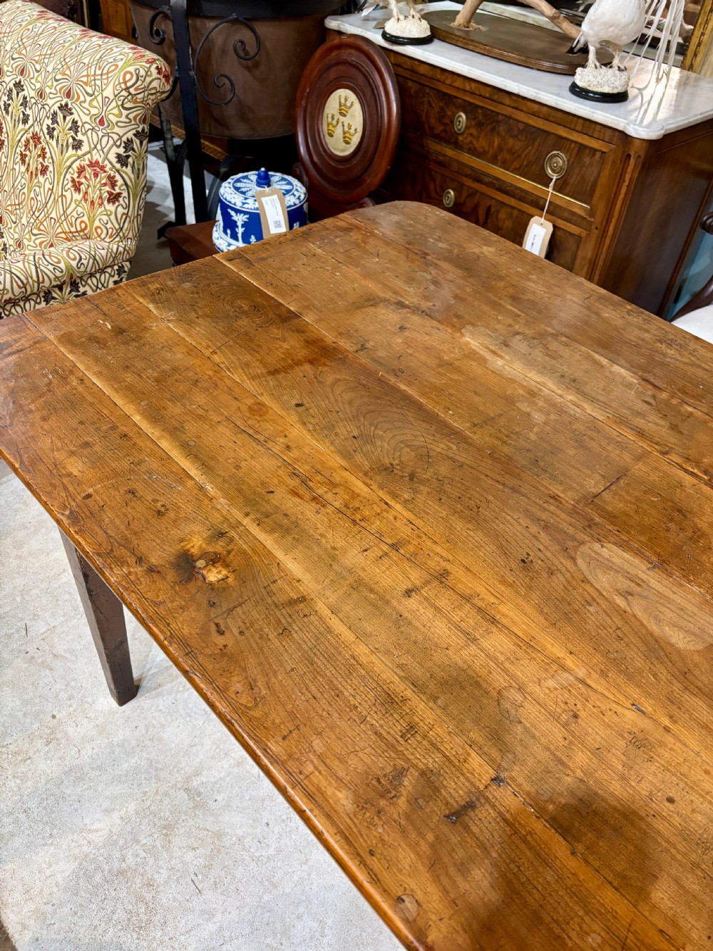 A long 19th-century French farmhouse dining table in warm brown wood with a polished plank top and square tapered legs. View VI