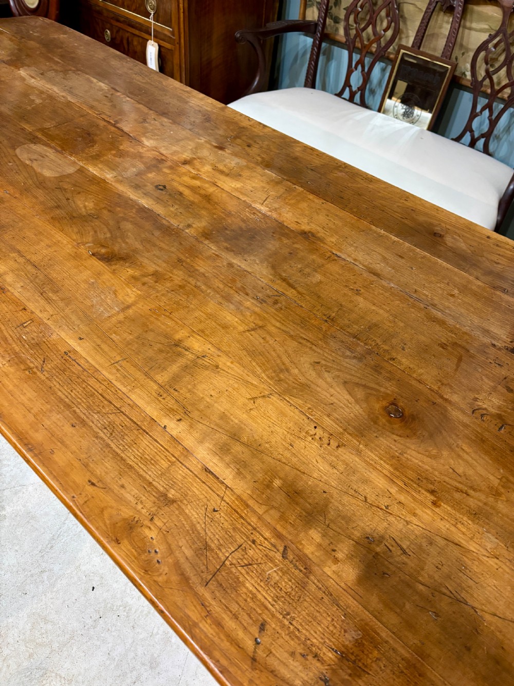 A long 19th-century French farmhouse dining table in warm brown wood with a polished plank top and square tapered legs. View VII