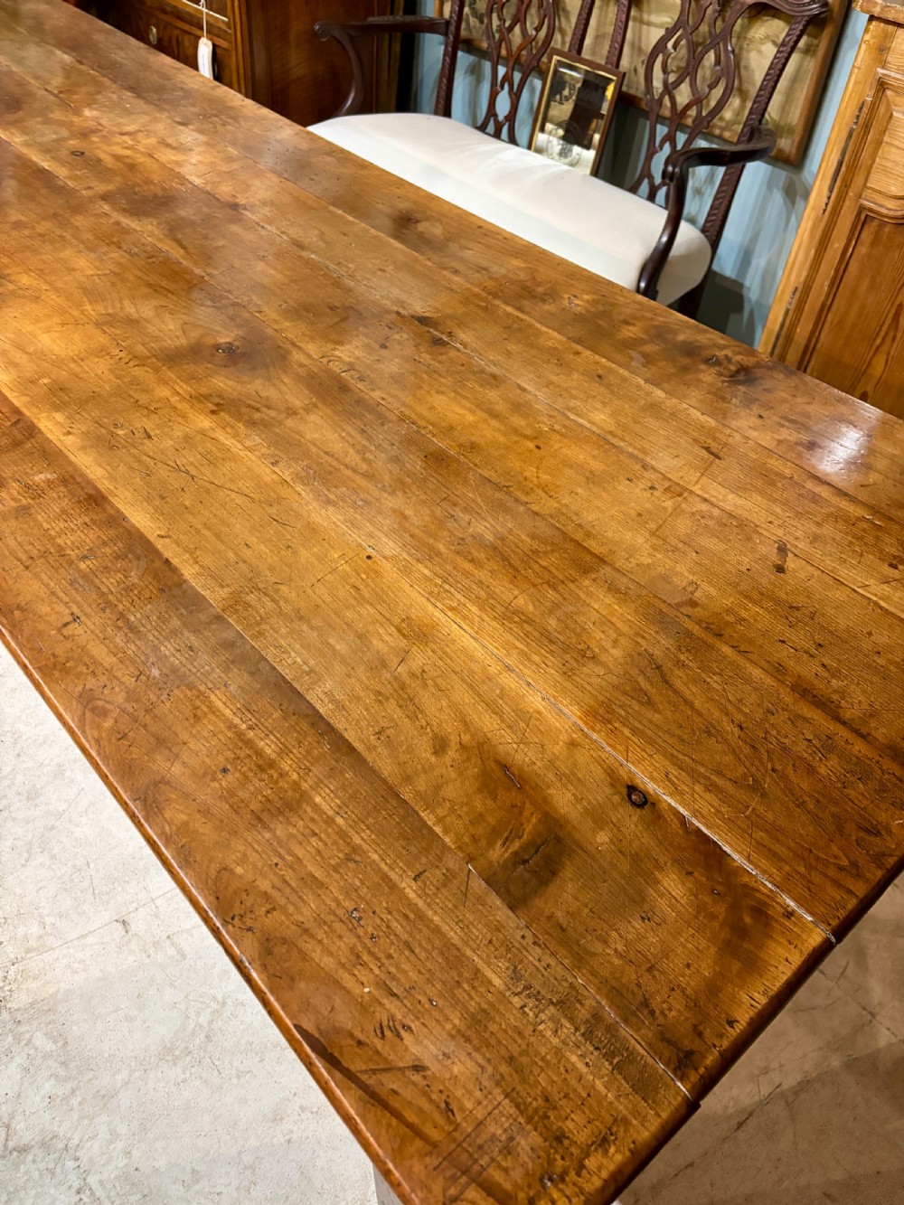 A long 19th-century French farmhouse dining table in warm brown wood with a polished plank top and square tapered legs. View VIII