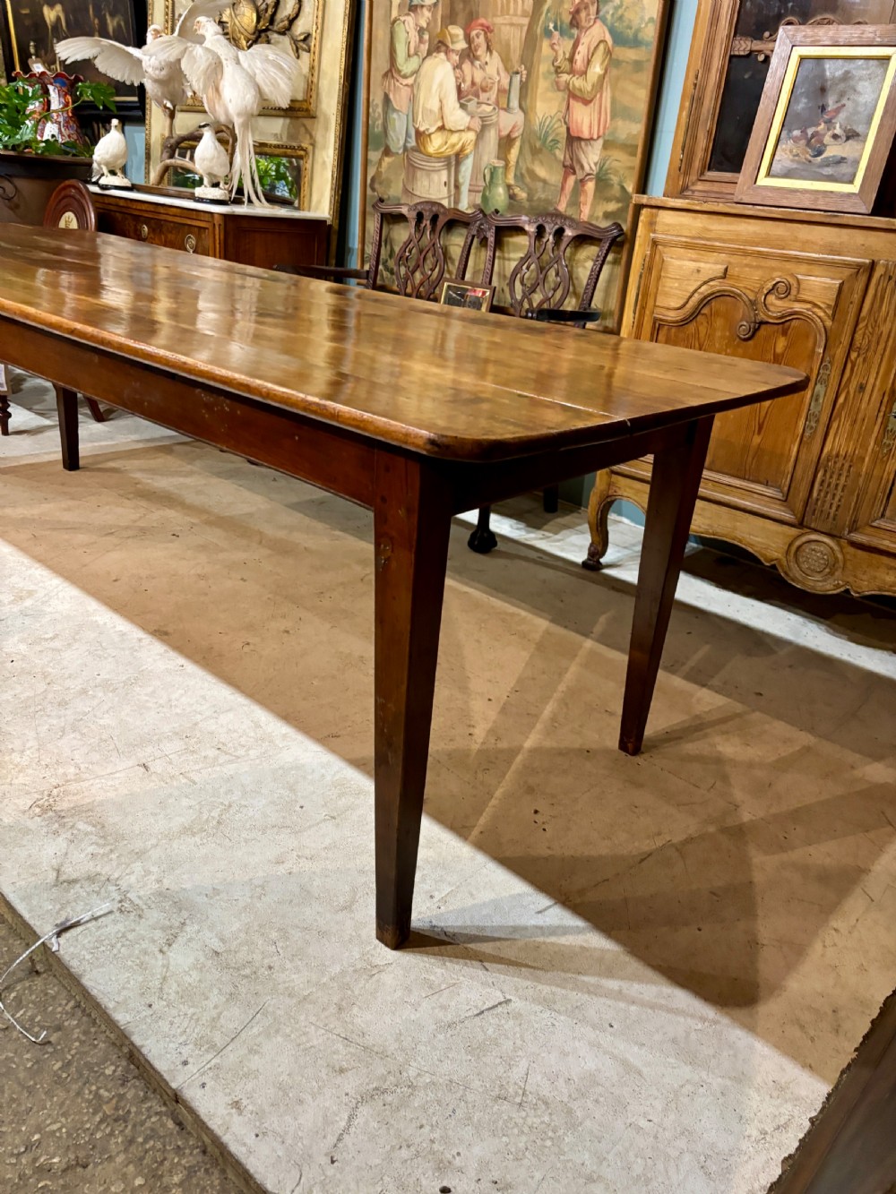 A long 19th-century French farmhouse dining table in warm brown wood with a polished plank top and square tapered legs. View IX