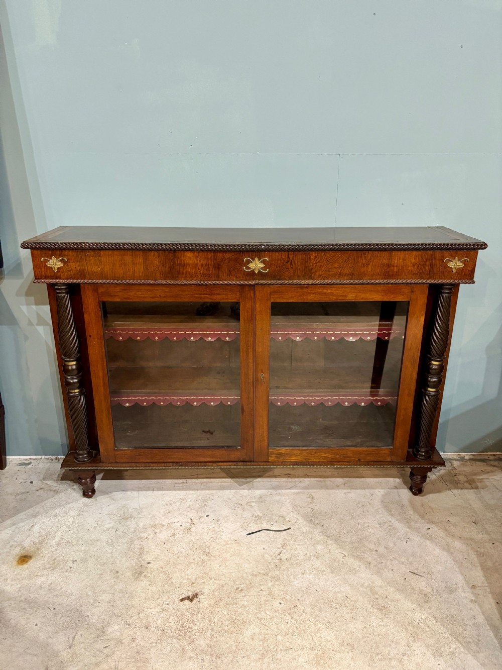 A 19th-century low rosewood bookcase featuring twin glazed doors flanked by spiral columns and decorated with brass rosette mounts.