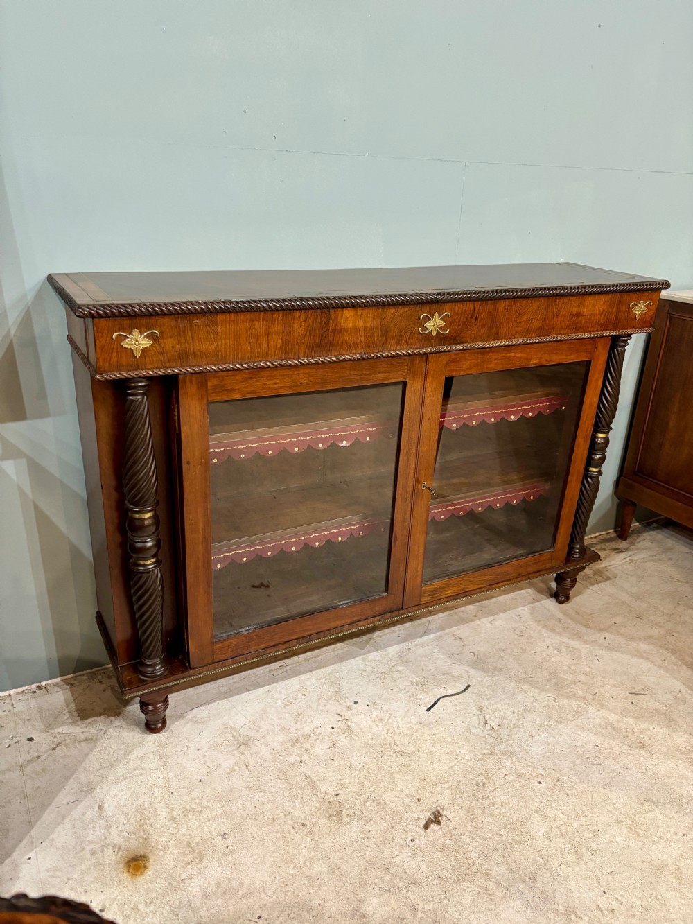 A 19th-century low rosewood bookcase featuring twin glazed doors flanked by spiral columns and decorated with brass rosette mounts. View III