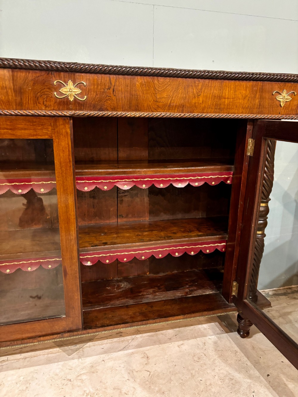 A 19th-century low rosewood bookcase featuring twin glazed doors flanked by spiral columns and decorated with brass rosette mounts. View IV