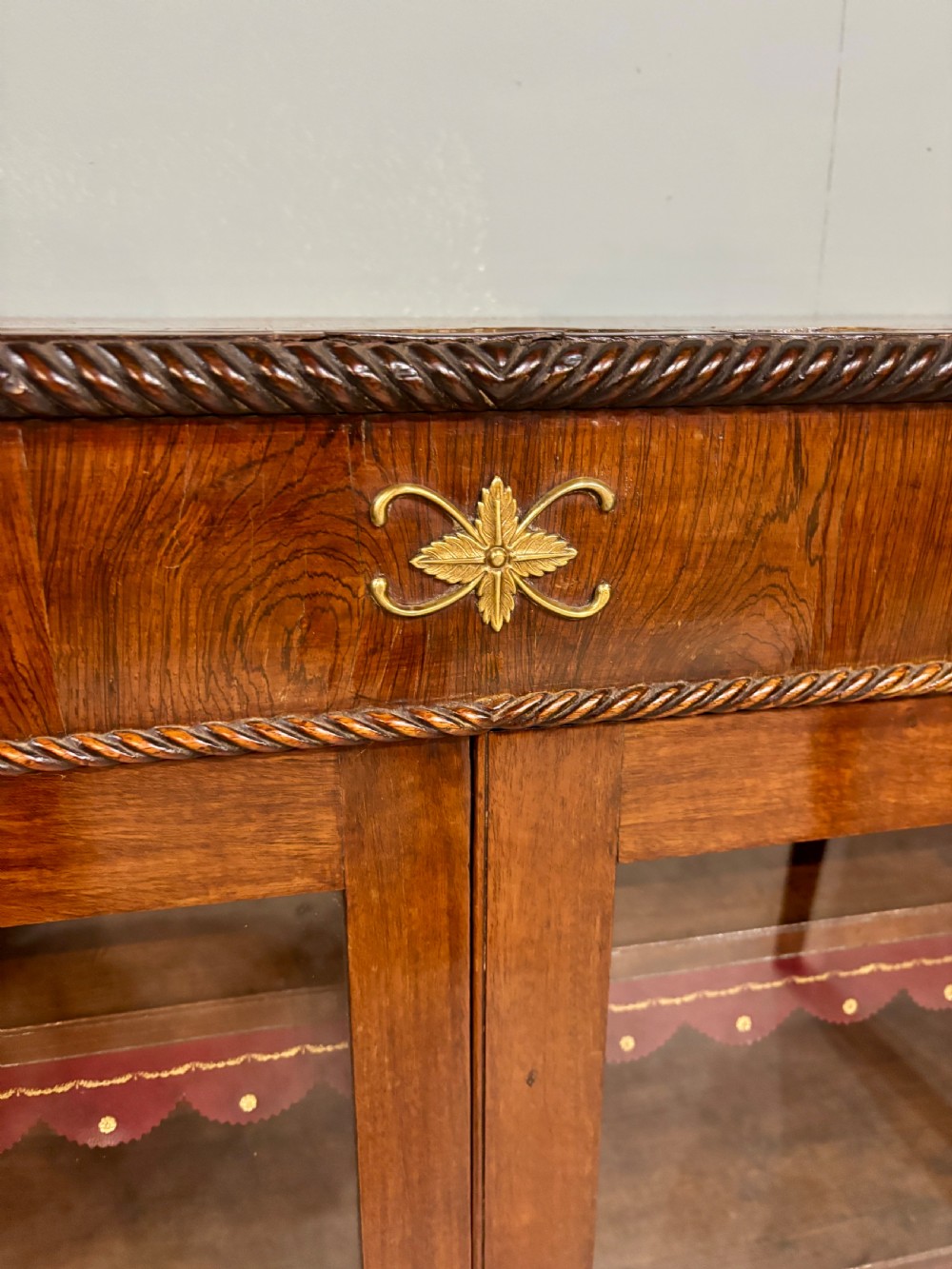 A 19th-century low rosewood bookcase featuring twin glazed doors flanked by spiral columns and decorated with brass rosette mounts. View VI