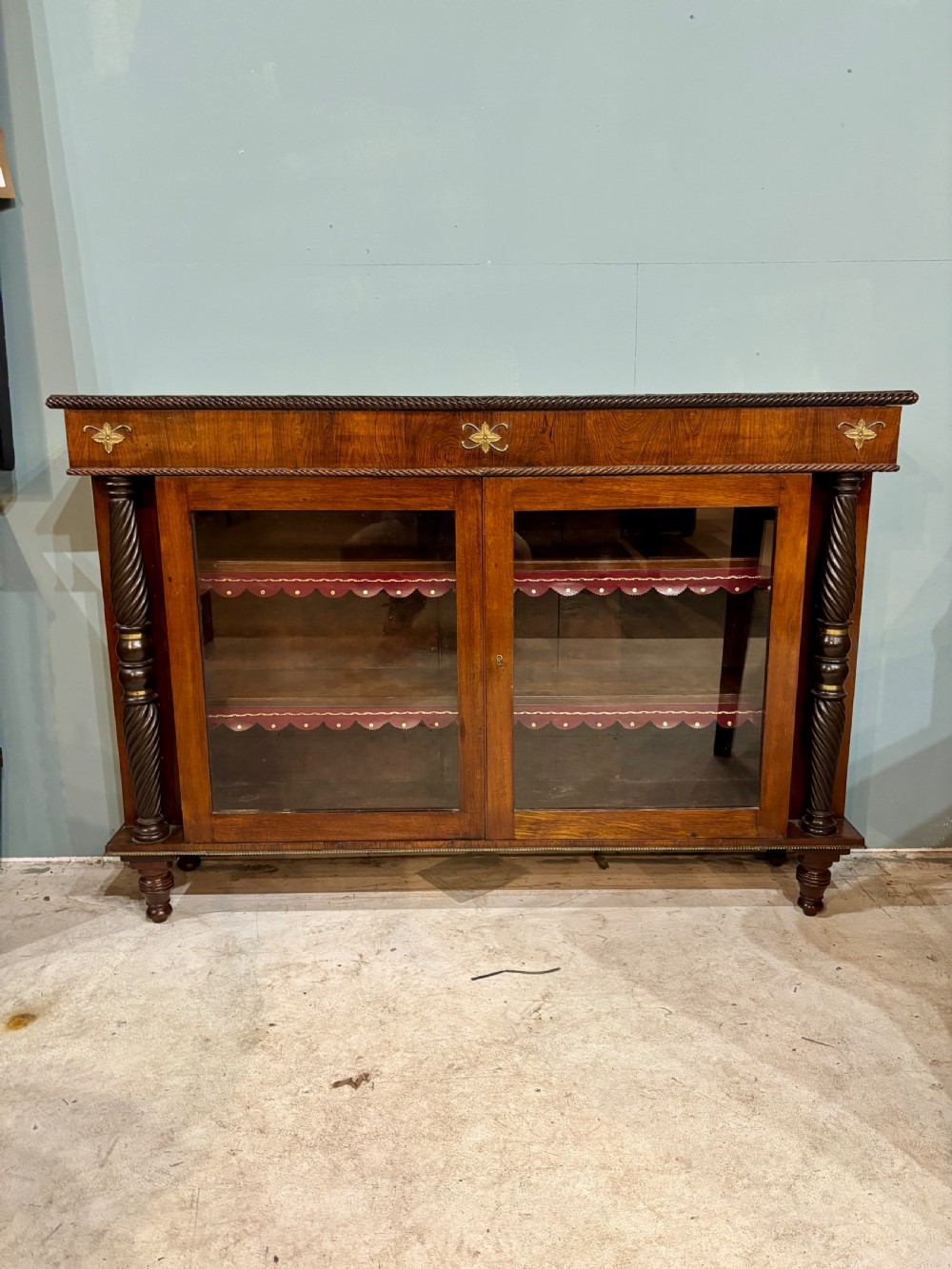 A 19th-century low rosewood bookcase featuring twin glazed doors flanked by spiral columns and decorated with brass rosette mounts. View VII