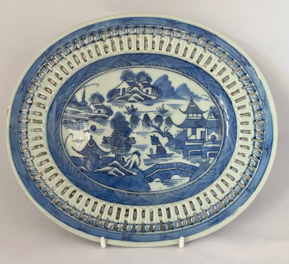 An oval blue and white porcelain Chinese export dish featuring a pierced reticulated border and a hand-painted landscape scene.